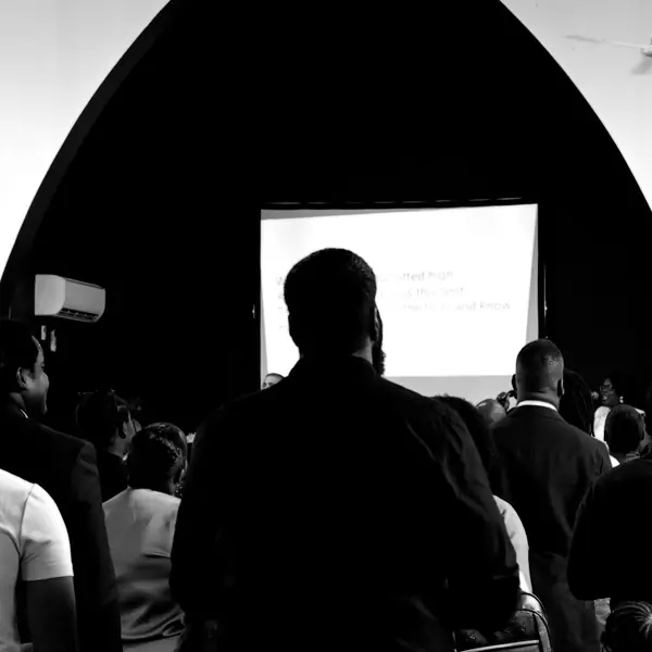 A man preaching in front of the screen